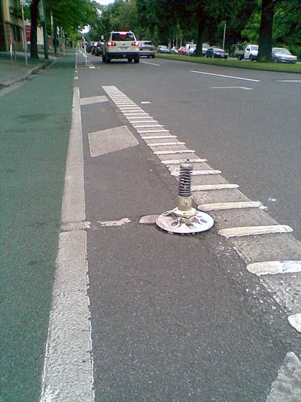 A stretch of the eastbound bike lane on Albert St, East Melbourne, showing a close-up of a broken pole mounting.